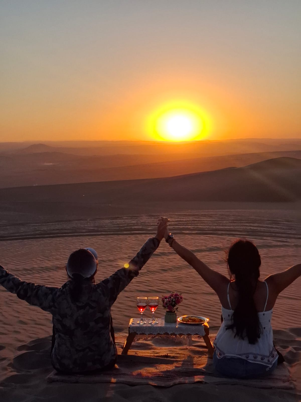 Pareja disfrutando de un picnic al atardecer en la costa de Paracas